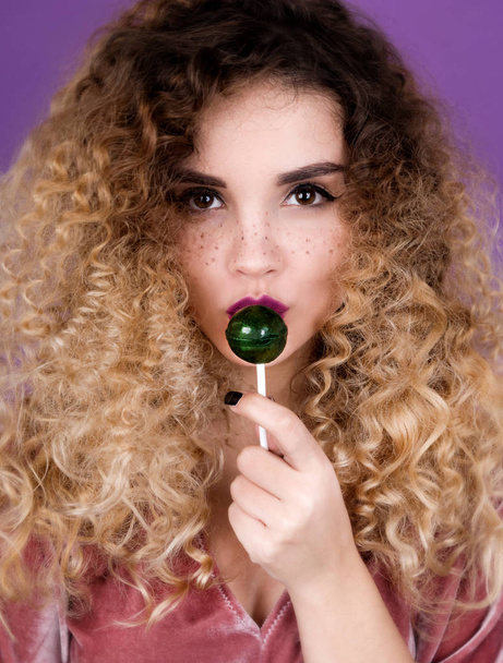 Young woman with freckles and curly hair holding lollipop - Photo, Image