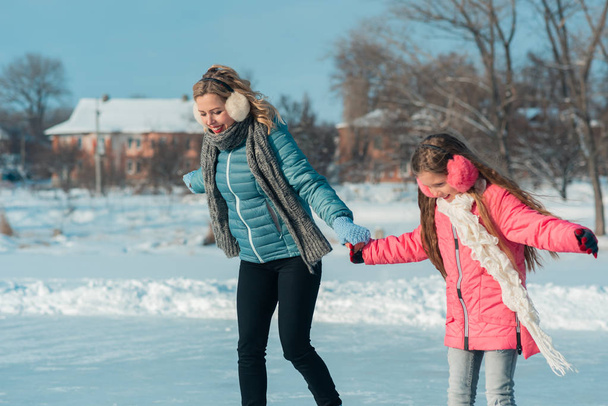 Young family have fun on the ice area in a snowy park - Photo, Image