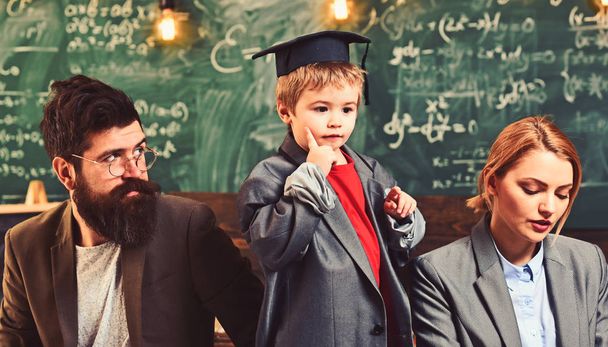 Genius son teach mother and father students. Little child play teacher with woman and man. Family together on chalkboard with bulbs, ideas. Back to school. Future and education concept - Photo, Image