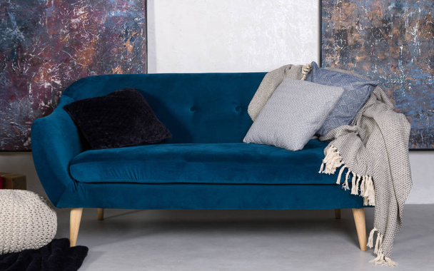 Військово-синій ретро розкладний диван з подушками і сірою ковдрою
 - Фото, зображення