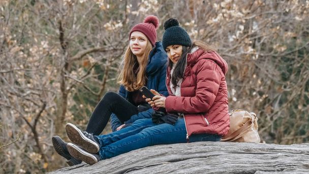 Two girls sit on a rock in Central Park New York - Fotoğraf, Görsel