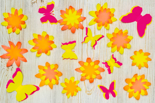 Colorful paper butterflies and flowers on wooden background. Childrens developmental activity. Application and origami - Valokuva, kuva