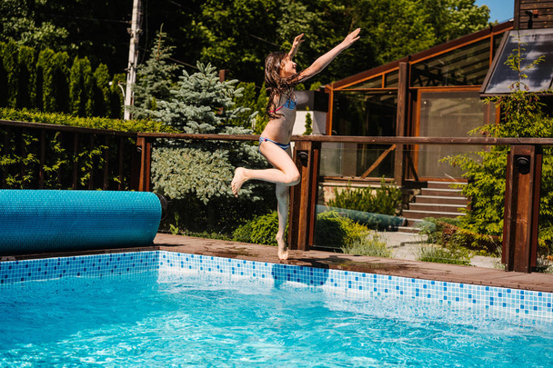 Happy girl jumping in the the pool - Фото, зображення