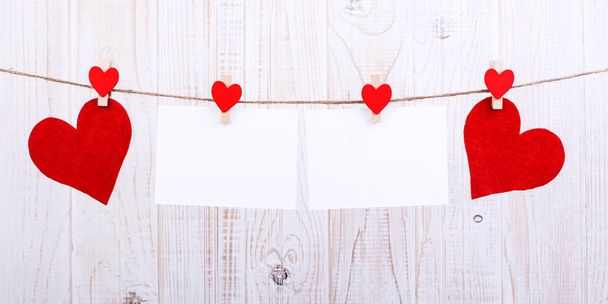 Handmade red felt hearts and white paper hanging on rope with clothespins. Concept, banner, copy space, form. - Photo, Image