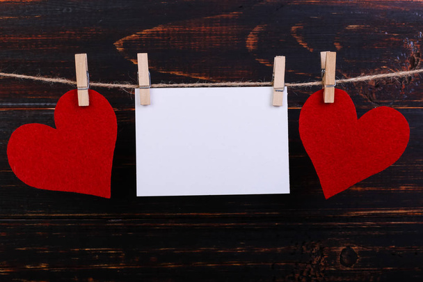 Handmade red felt hearts and white paper hanging on rope with clothespins. Concept, banner, copy space, form. - Zdjęcie, obraz