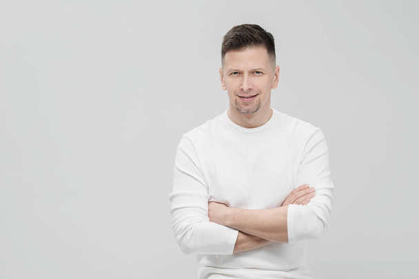 Futuristic handsome bearded brunet man 40s years in white clothes on a white background with folded arms, portrait. God, teacher and boss. - Foto, Bild