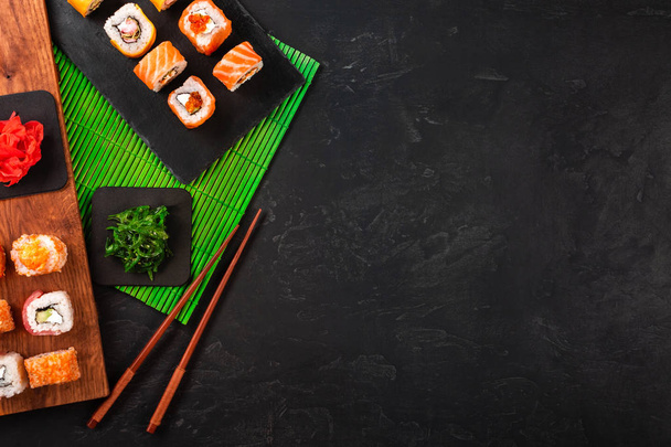 Sushi asetettu wasabi ja inkivääri musta kivi tarjotin musta pöytä. Yläkuva
. - Valokuva, kuva