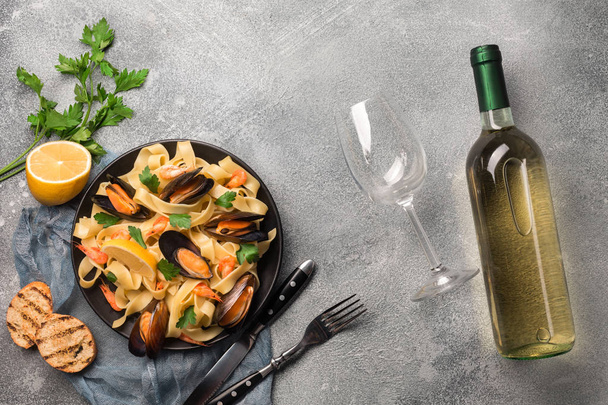 Ζυμαρικά με θαλασσινά και το λευκό κρασί στο πέτρινο τραπέζι. Μύδια και γαρίδες. Κάτοψη - Φωτογραφία, εικόνα