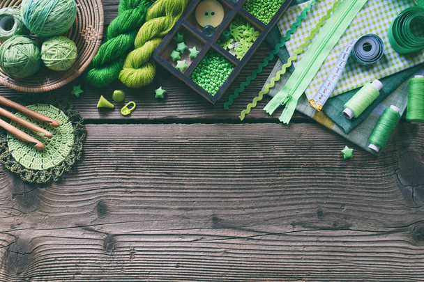 Acessórios verdes para bordado em fundo de madeira. Tricô, crochê, bordado, costura. Pequenos negócios. Rendimento do hobby. DIY Handmade
 - Foto, Imagem