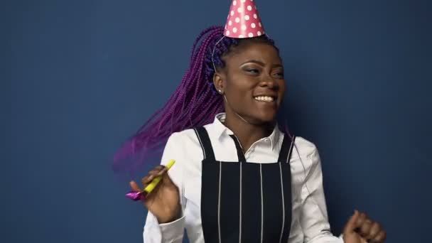Handsome african girl in birthday hat dancing on the blue background. - Záběry, video