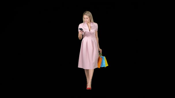 Shopping Frau mit Taschen SMS-Nachricht auf dem Smartphone während des Gehens, Alpha-Kanal - Filmmaterial, Video