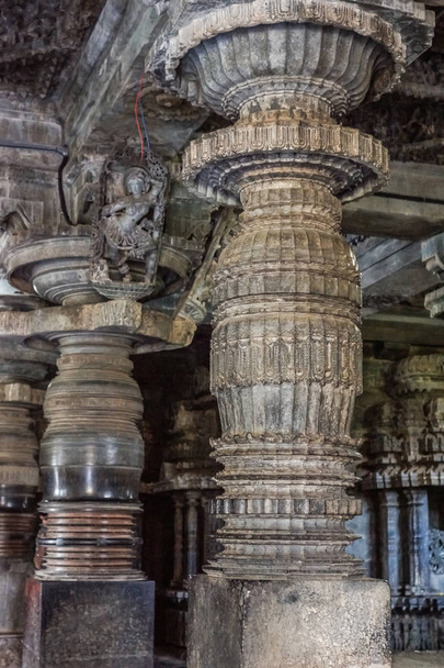 Halebidu, Karnataka, Índia - 2 de novembro de 2013: Templo Hoysaleswara de Shiva. Requintadamente decorado pilar e Madanakai ou Salabhanjika, uma estátua menina dança contra teto no topo do pilar. Pedra acastanhada cinzenta
. - Foto, Imagem