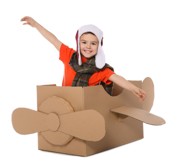 Cute little boy playing with cardboard airplane on white background - Fotoğraf, Görsel