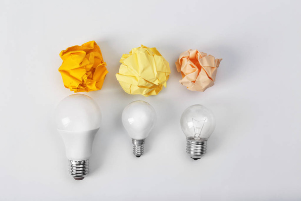 Composition with lamp bulbs and crumpled paper balls on white background, top view. Creative concept - Foto, Bild