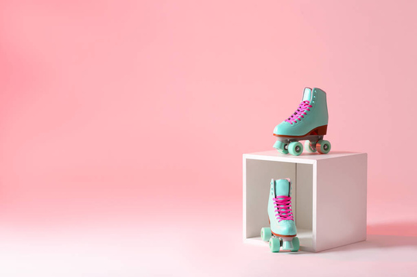 Pair of vintage roller skates and storage cube on color background. Space for text - Fotó, kép
