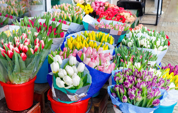 Colorful tulips, roses and other flowers in pots at entry to small flower shop  - Foto, Imagem