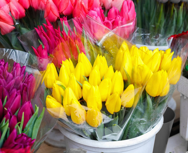 Tulipas coloridas, rosas e outras flores em vasos à entrada da pequena loja de flores
  - Foto, Imagem