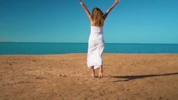 Ευτυχισμένος κορίτσι σε λευκό φόρεμα τρέχει προς τη θάλασσα και χαίρεται - Πλάνα, βίντεο