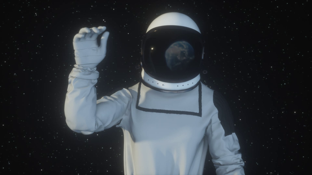 Astronaut in outer space waving the planet Earth with his hand, the earth is reflected in the spacesuit - Footage, Video