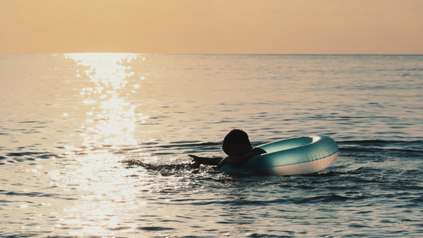 Kisfiú játszik a vízben a gumi gyűrű nyári szünetben a tengeren - Felvétel, videó