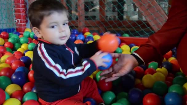 Eineinhalbjähriger Junge spielt auf Kinderspielplatz mit bunten Kugeln und Boxsäcken - Filmmaterial, Video