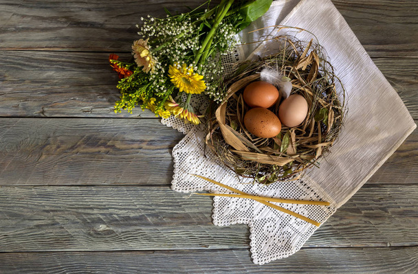 La composición de Pascua. Huevos, un ramo de gerberas coloridas y velas de iglesia en la mesa de madera de cerca
. - Foto, Imagen