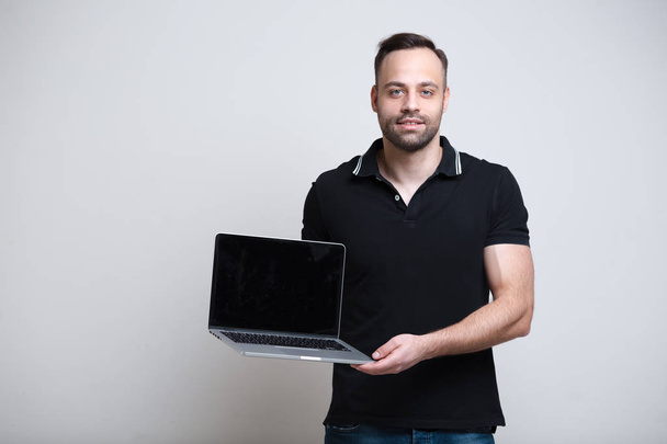 Młody mężczyzna, trzymając laptop w ręce na białym tle - Zdjęcie, obraz