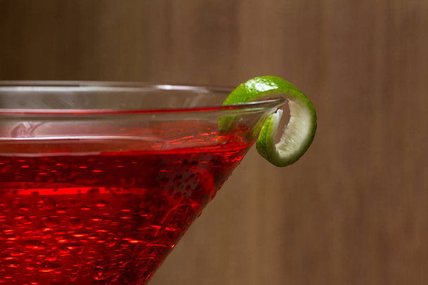 Ahşap arka plan üzerinde bir kireç ile süslenmiş bir martini cam servis Cosmo, yakın çekim - Fotoğraf, Görsel