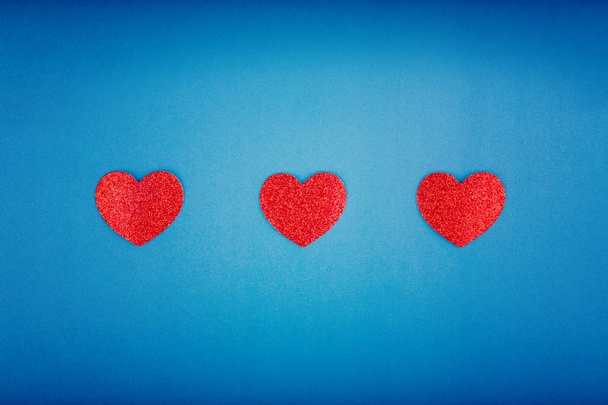 Szczęśliwy Valentine Day. Piękne kartki Tapety z trzy czerwone serca w centrum na niebieskim tle. Gradientowe tło stonowanych. Koncepcja miłości poligamia i lutego wakacje.  - Zdjęcie, obraz