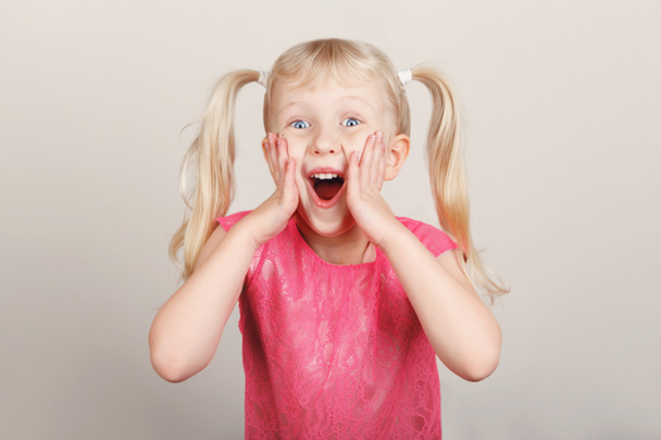 Retrato de close-up de menina pré-escolar branca loira branca surpreendida fazendo rostos na frente da câmera. Criança sorrindo rindo posando em estúdio em fundo claro. Criança expressando emoções
 - Foto, Imagem