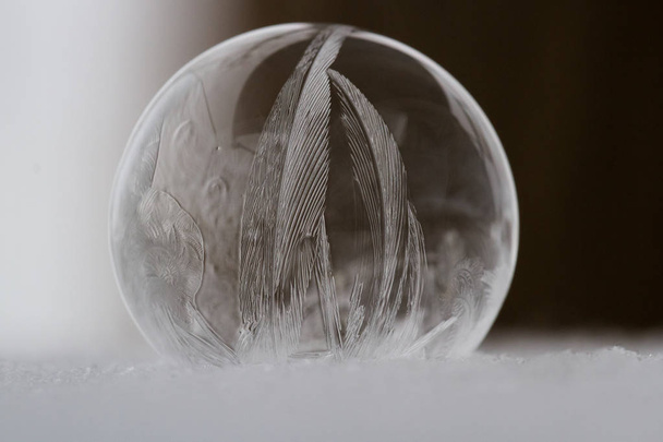 Close up of a small soap bubble freezing rapidly due to extreme cold temperatures in winter - Foto, imagen