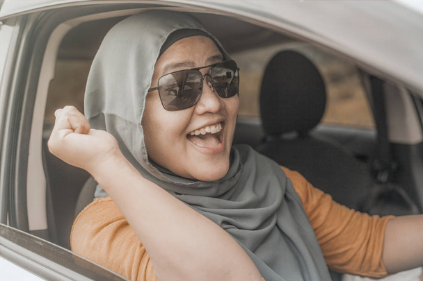 Portrait of Asian muslim lady smiling while drive her car, lifestyle having fun leisure in vacation trip, car ride sharing concept - Foto, Imagen