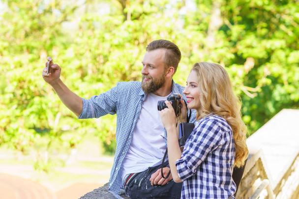 Man and woman taking photos with a camera and a smartphone. Love, traveling and relations concept. - Photo, image