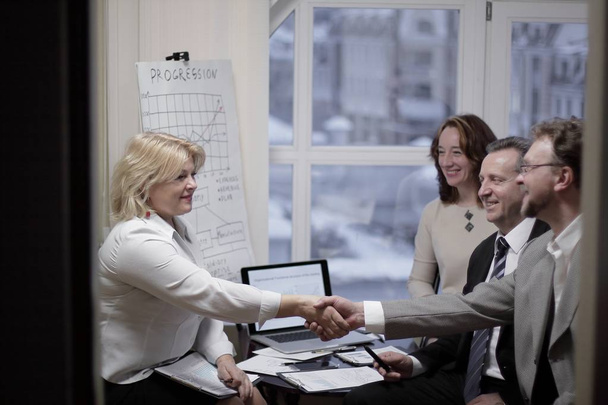 smiling business woman shaking hands with the investor - Foto, afbeelding