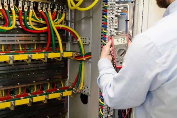 Service engineer working with electric device for testing electrical cabinet. - Photo, Image