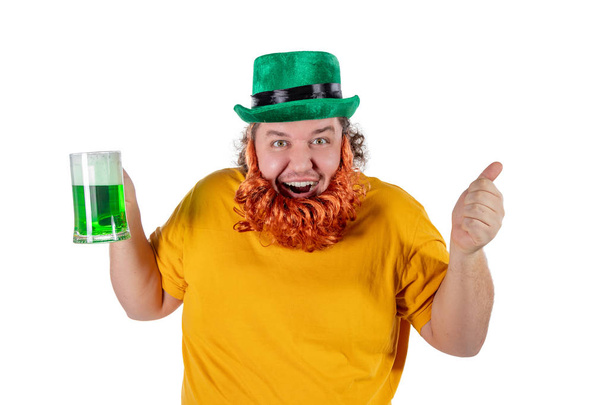 A smiling happy fat man in a leprechaun hat with green beer. He celebrates St. Patrick - Φωτογραφία, εικόνα
