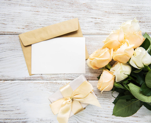 Rosas blancas y tarjeta de felicitación en una vieja mesa de madera
 - Foto, imagen