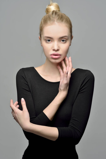 Portrait of the Beautiful blonde woman in a black posing in studio with grey background . - Фото, изображение