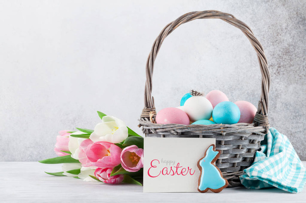 Easter greeting card with tulip flowers, gingerbread cookies and easter eggs. In front of stone wall with space for your greetings - Foto, Imagen