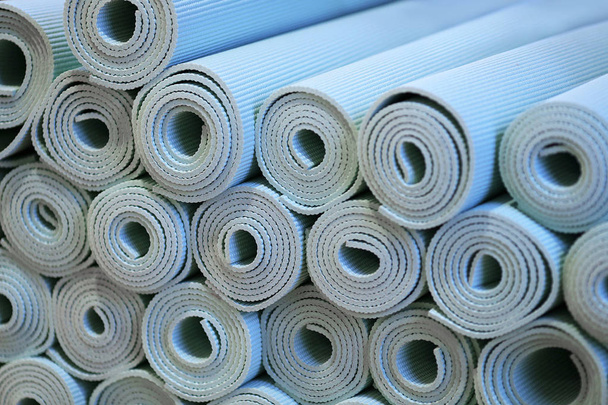 Una vasta collezione di arrotolati blu schiuma stuoie di yoga sono in mostra in una palestra di fitness
. - Foto, immagini