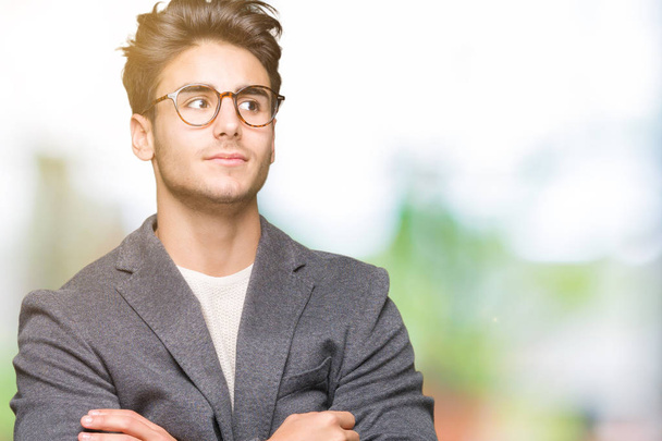 Young business man wearing glasses over isolated background smiling looking side and staring away thinking. - Foto, afbeelding