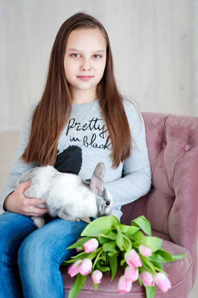 Girl with a rabbit in her arms and with pink tulips - Foto, Imagen
