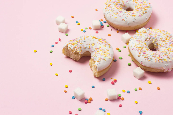 新鮮なおいしい甘いドーナツ、色とりどりの装飾キャンディー、ピンクの背景の砂糖の立方体。ファーストフード、おいしい朝食、焼きたてのペストリー ベーカリー コンセプト - 写真・画像