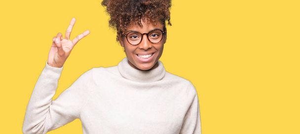 孤立した背景表示と指で上向きに眼鏡をかけて美しい若いアフリカ系アメリカ人女性数は自信を持って、幸せな笑みを浮かべている間 2. - 写真・画像