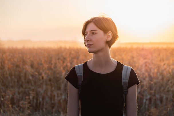 Backlit portrait of a woman in sunset. Female person standing in evening sunlight at a field - Foto, Imagem