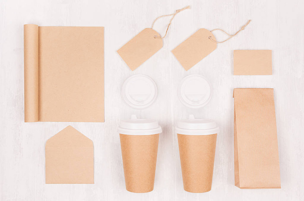 Coffee branding identity mockup - set of two brown paper cups with blank notebook, label, card, cap, envelope, packet on white wood board, top view. - Foto, Imagem