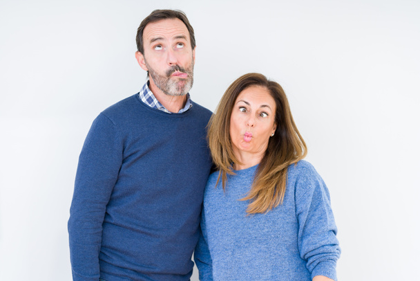 Beautiful middle age couple in love over isolated background making fish face with lips, crazy and comical gesture. Funny expression. - Photo, Image