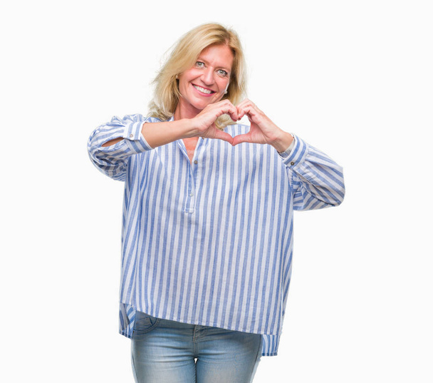 Блондинка середнього віку бізнес-леді над ізольованим тлом посміхається в любові, показуючи серцевий символ і форму руками. Романтична концепція
. - Фото, зображення