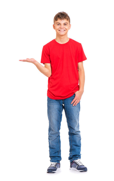 Full length portrait of teen boy holding something imaginary on palm, isolated on white background. Funny teenager showing copyspace on palm. Handsome child looking at camera and smiling. - Photo, image