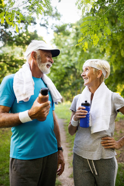Senior couple jogging and running outdoors in nature - Photo, image